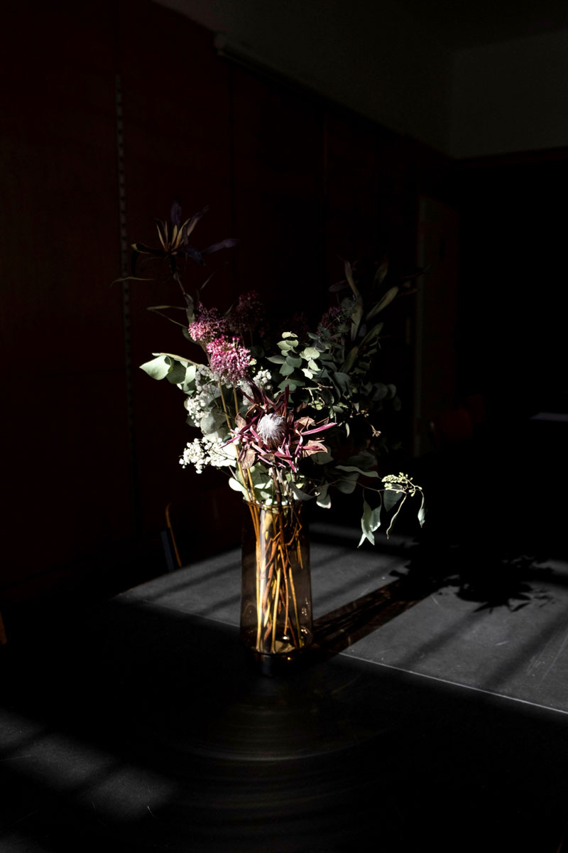 Stillleben einer Vase mit getrockneten Blumen auf einem schwarzen Tisch