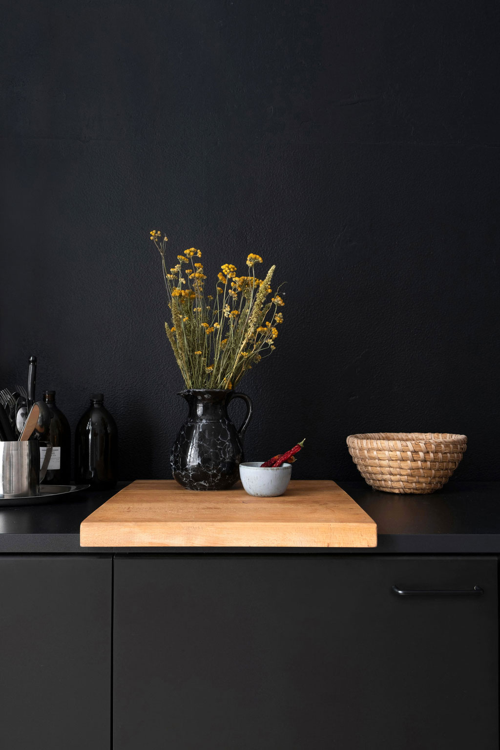 Fotografie eines Stilllebens vor schwarzer Wand, Vase mit einem Strauß Blumen