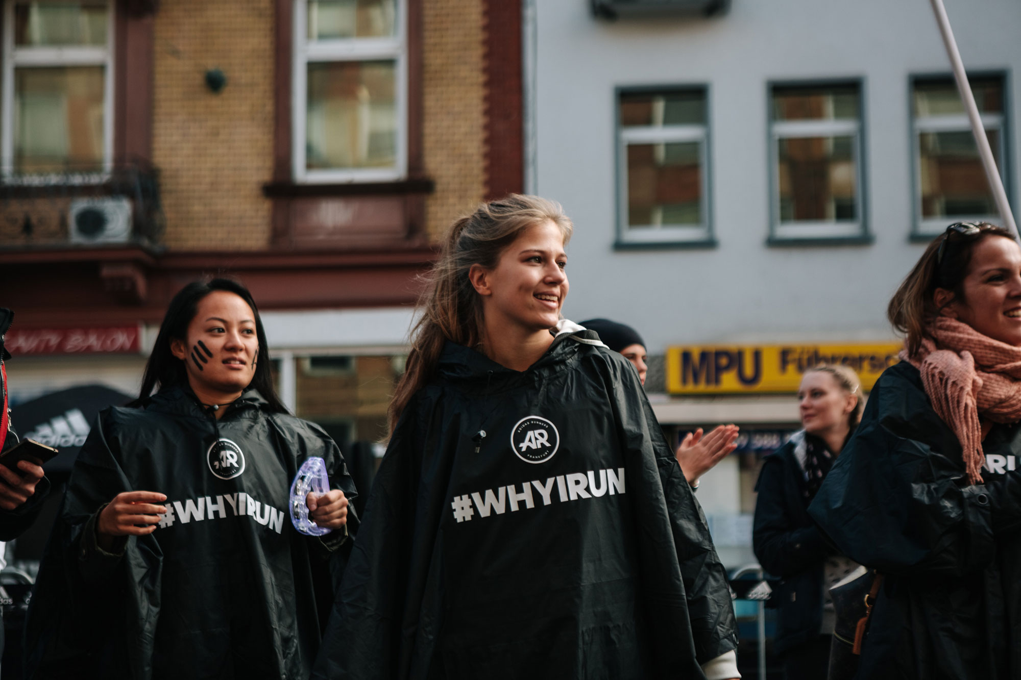Zwei Mädchen an der Cheering-Base beim Frankfurt Marathon in schwarzen Regenponchos