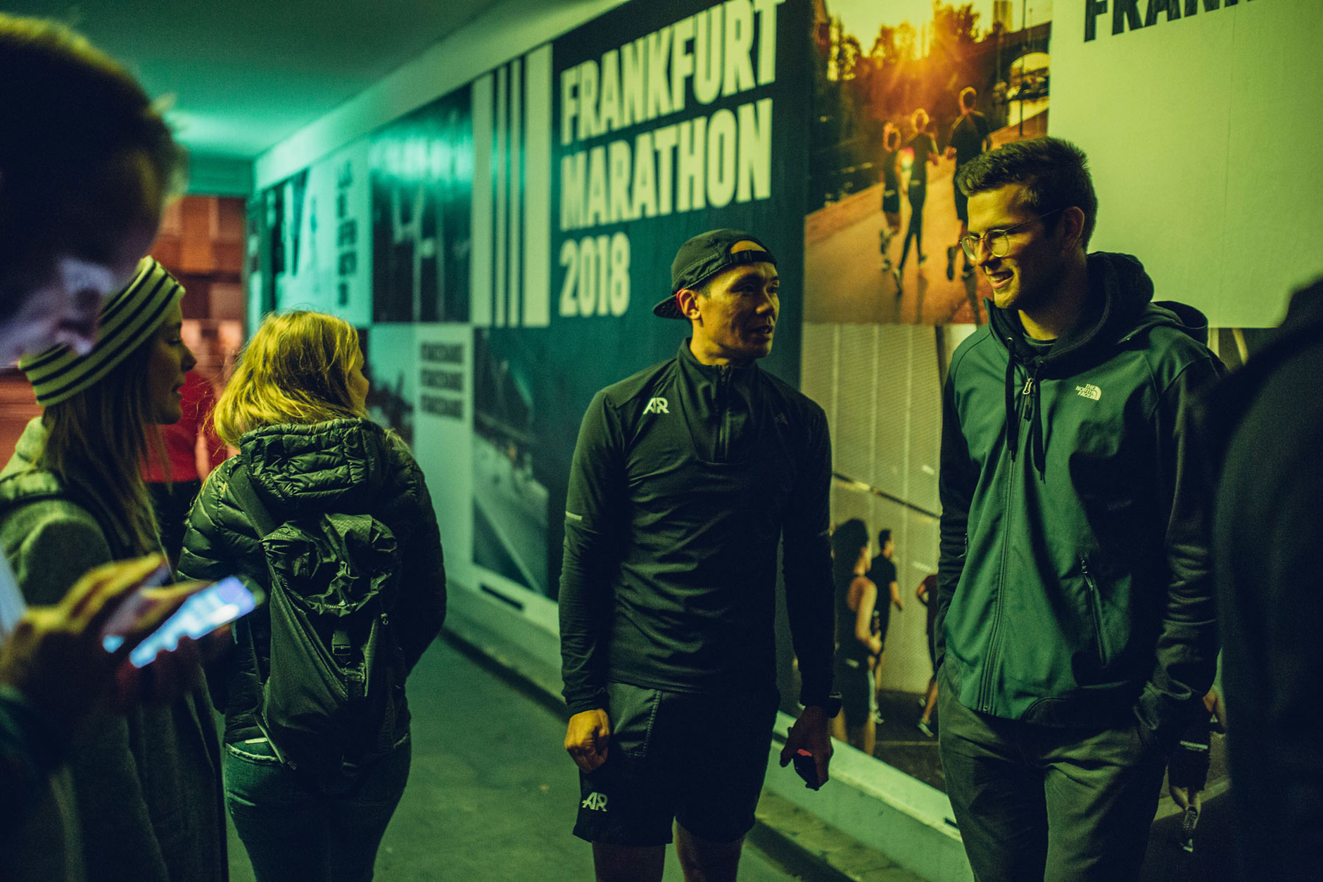 Unterhaltende Menschen vor der Wandgrafik der adidas Runners
